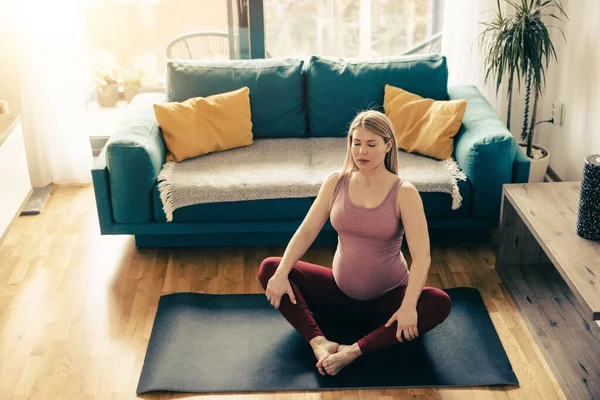 年轻的孕妇早上在家练习瑜伽 她在做伸展运动 — 图库照片