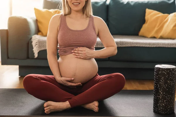 被一个无法辨认的孕妇在家里练习瑜伽射中了 她在运动垫和伸展运动上锻炼 — 图库照片