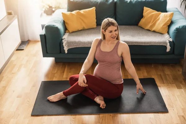 年轻的孕妇早上在家里锻炼 她在运动垫上锻炼 在客厅里舒展筋骨 — 图库照片