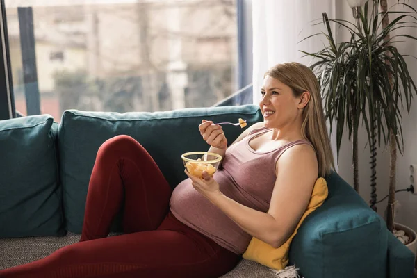 Leende Ung Gravid Kvinna Äter Färsk Fruktsallad Medan Koppla Hennes — Stockfoto