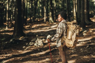 Sırt çantalı olgun siyah kadın dağlarda tek başına yürüyüş yapıyor..