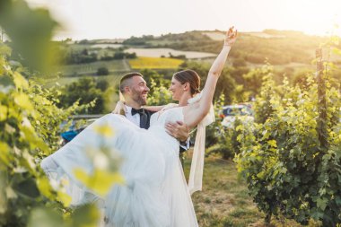 Neşeli damat gelinini taşırken ve döndürürken düğün günlerinde üzüm bağında eğlenirken.