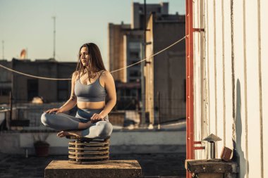 Relaxed woman practicing yoga meditating on a rooftop terrace