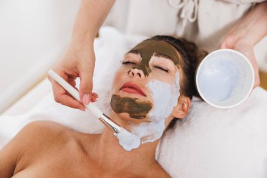 Güzel genç bir kadın kaplıcada nemlendirici maske tedavisi görüyor..