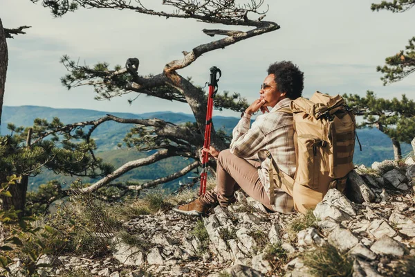 成熟的黑人妇女在远足探险时坐在山崖上欣赏风景 — 图库照片