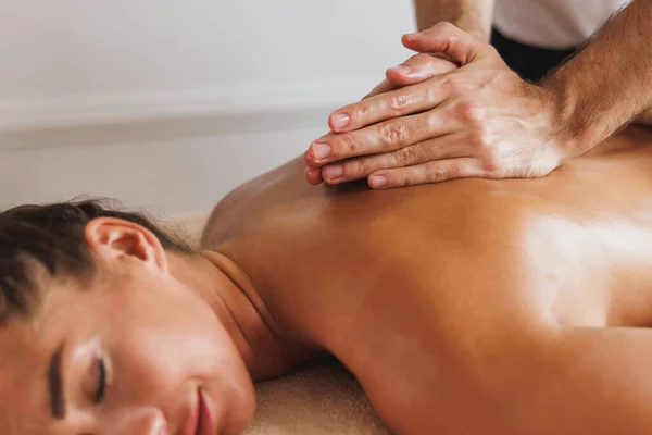 Close-up shoot of a woman receiving a back massage from a professional at the spa.