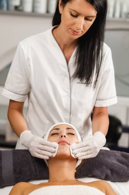 Güzellik salonunda yüz bakımı yapan güzel bir kadının fotoğrafı..