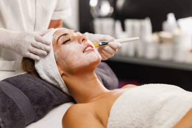 Güzeller güzeli genç bir kadının güzellik salonunda maske taktırırken fotoğrafı..