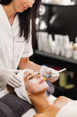 Güzeller güzeli genç bir kadının güzellik salonunda maske taktırırken fotoğrafı..