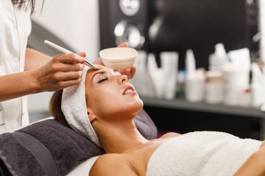 Güzeller güzeli genç bir kadının güzellik salonunda maske taktırırken fotoğrafı..