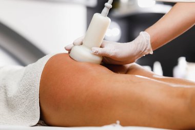Güzellik salonunda selülit karşıtı masaj yaptıran tanınmamış bir kadının fotoğrafı. Yağ oranını düşürmek için ultrason havza tedavisi görüyor..