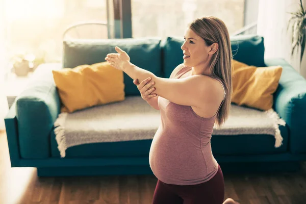 年轻的孕妇早上在家里锻炼 她在做伸展运动 — 图库照片