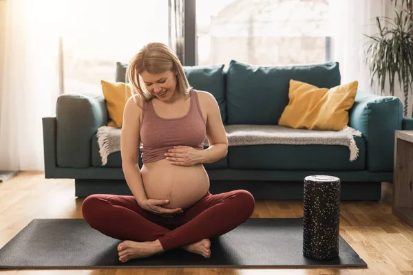 一名身穿运动服的孕妇正在客厅里放松和锻炼 以增进她的健康 — 图库照片
