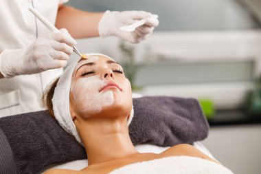 Güzeller güzeli genç bir kadının güzellik salonunda maske taktırırken fotoğrafı..