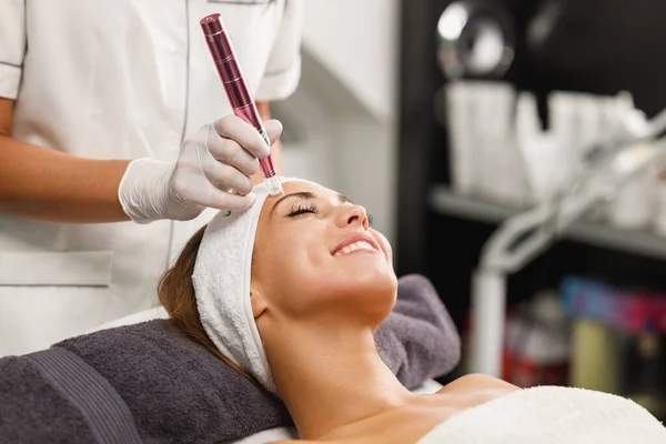 Shot of a beautiful young woman on a facial dermapen micro-needling treatment at the beauty salon.