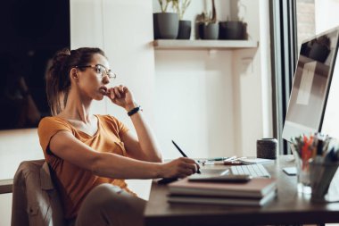 Genç bayan serbest çalışan ev ofisinden bilgisayarla uğraşırken düşünceli görünüyor..