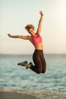 Genç ve zinde bir kadın denize yakın egzersizlerinden sonra eğleniyor ve dinleniyor..