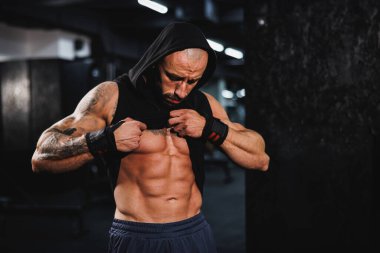 Spor salonunda egzersiz yaptıktan sonra mükemmel kaslarını gösteren genç kaslı bir vücut geliştirici..