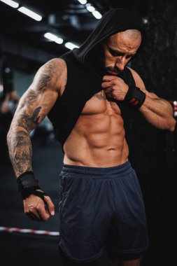 Spor salonunda egzersiz yaptıktan sonra mükemmel kaslarını gösteren genç kaslı bir vücut geliştirici..