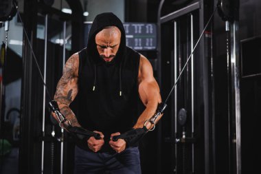 Genç kaslı bir vücut geliştirici göğüs kasları için spor makinesinde sıkı antrenman yapıyor..