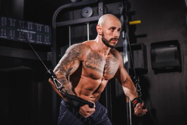 Genç, kaslı bir fitness adamı spor makinesinde göğüs kasları için sıkı antrenman yapıyor..