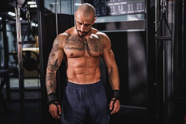 Spor salonunda idman yaptıktan sonra mükemmel kaslarını gösteren genç bir fitness oyuncusunun fotoğrafı..