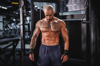 Spor salonunda idman yaptıktan sonra mükemmel kaslarını gösteren genç bir fitness oyuncusunun fotoğrafı..