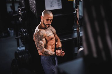 Spor salonunda egzersiz yaptıktan sonra mükemmel kaslarını gösteren genç bir fitness oyuncusunun fotoğrafı..