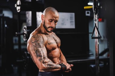 Spor salonunda egzersiz yaptıktan sonra mükemmel kaslarını gösteren genç kaslı bir vücut geliştirici..