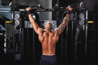 Genç kaslı bir fitness adamı spor salonunda barfiks egzersizi yapıyor..