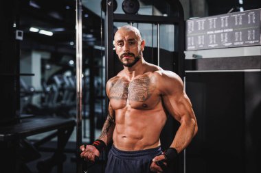Genç kaslı bir vücut geliştirici göğüs kasları için spor makinesinde sıkı antrenman yapıyor..