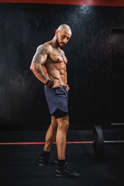 Spor salonunda egzersiz yaptıktan sonra mükemmel kaslarını gösteren genç kaslı bir vücut geliştirici..