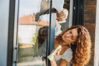 Bir dairede, evde ya da otelde cam temizleyen ve yıkayan bir kadın.