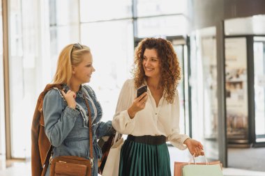 İki gülümseyen kadının alışveriş merkezinde eğlenmek için ara verişini..