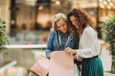 Kara Cuma ya da Siber Pazartesi satışları sırasında alışveriş merkezine alışverişe giden iki güzel ve gülümseyen kadının fotoğrafı..