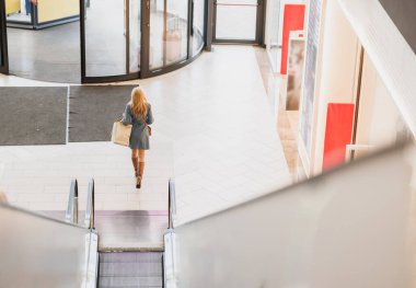 Kara Cuma ya da Siber Pazartesi satışları sırasında alışveriş merkezlerinde çanta taşıyan çekici bir kadının arka görünüşü.