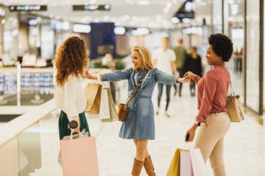 Üç çekici genç kadının alışveriş merkezinde eğlenirken ve birlikte alışveriş yaparken çekilmesi..