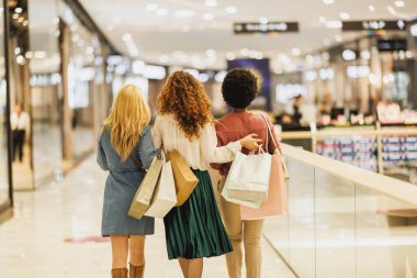 Üç kadın en iyi arkadaşın alışveriş merkezinde eğlenirken, eğlenirken ve kucaklaşırken arka planda görüntüsü..