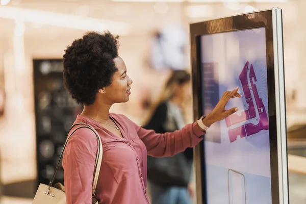 Shot of a mature African-American woman looking for a store on a map at the shopping mall.