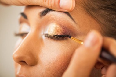 Güzel genç mankene göz kalemi sürmeye hazırlanan bir makyöz adama yaklaş..