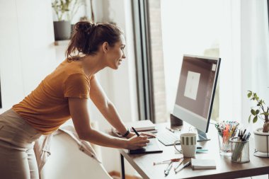 Ev ofisinden bilgisayarla çalışan yaratıcı genç bir kadın..