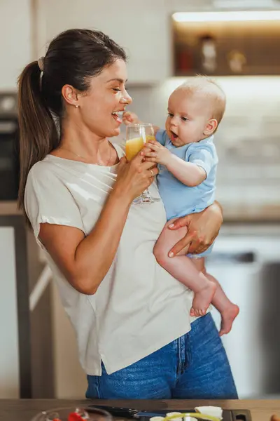 Junge Fürsorgliche Mutter Hält Ihr Baby Und Ein Glas Saft — Stockfoto
