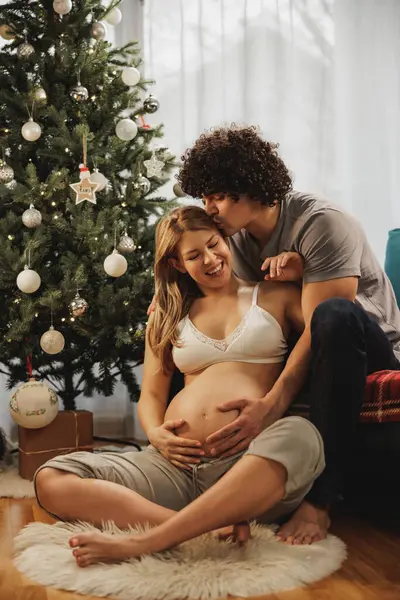 Pareja Embarazada Sentada Suelo Junto Árbol Navidad Casa Cogida Mano — Foto de Stock