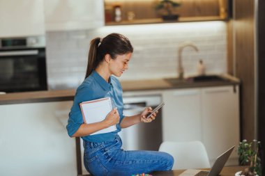 İş kadını akıllı telefon kullanıyor ve ev ofisinde çalışırken mola veriyor..