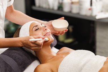 Güzeller güzeli genç bir kadının güzellik salonunda maske taktırırken fotoğrafı..