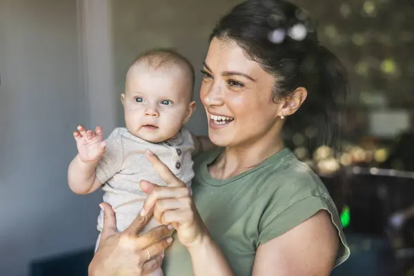 Lächelnde Mutter Schaut Aus Dem Fenster Während Sie Ihr Baby — Stockfoto