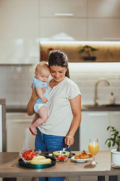 Multitasking Mutter Hält Ihr Baby Während Sie Hause Gesunde Mahlzeiten — Stockfoto