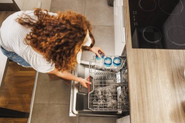 Modern bir mutfakta bardakları bulaşık makinesine koyan bir kadının en iyi görüntüsü..