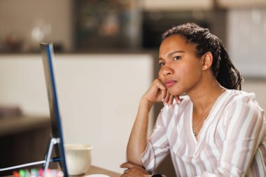 Afrikalı iş kadını ev ofisinden bilgisayarla uğraşırken düşünceli görünüyor..