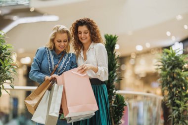 Kara Cuma ya da Siber Pazartesi satışları sırasında alışveriş merkezlerinde alışveriş torbaları taşıyan iki çekici kadının kesilen görüntüleri..